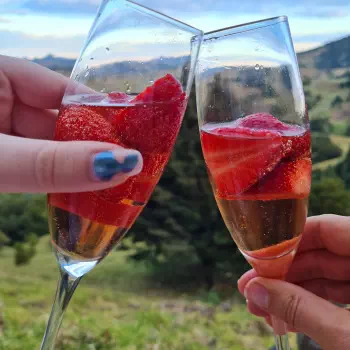 Two glasses clinking together filled with sparkling rose and strawberries