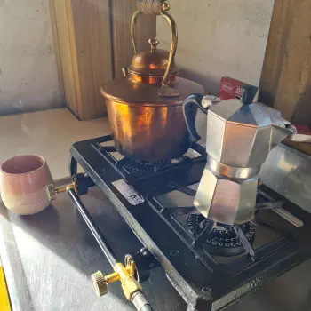 A kettle and a coffee maker on the gas stove in the cabin